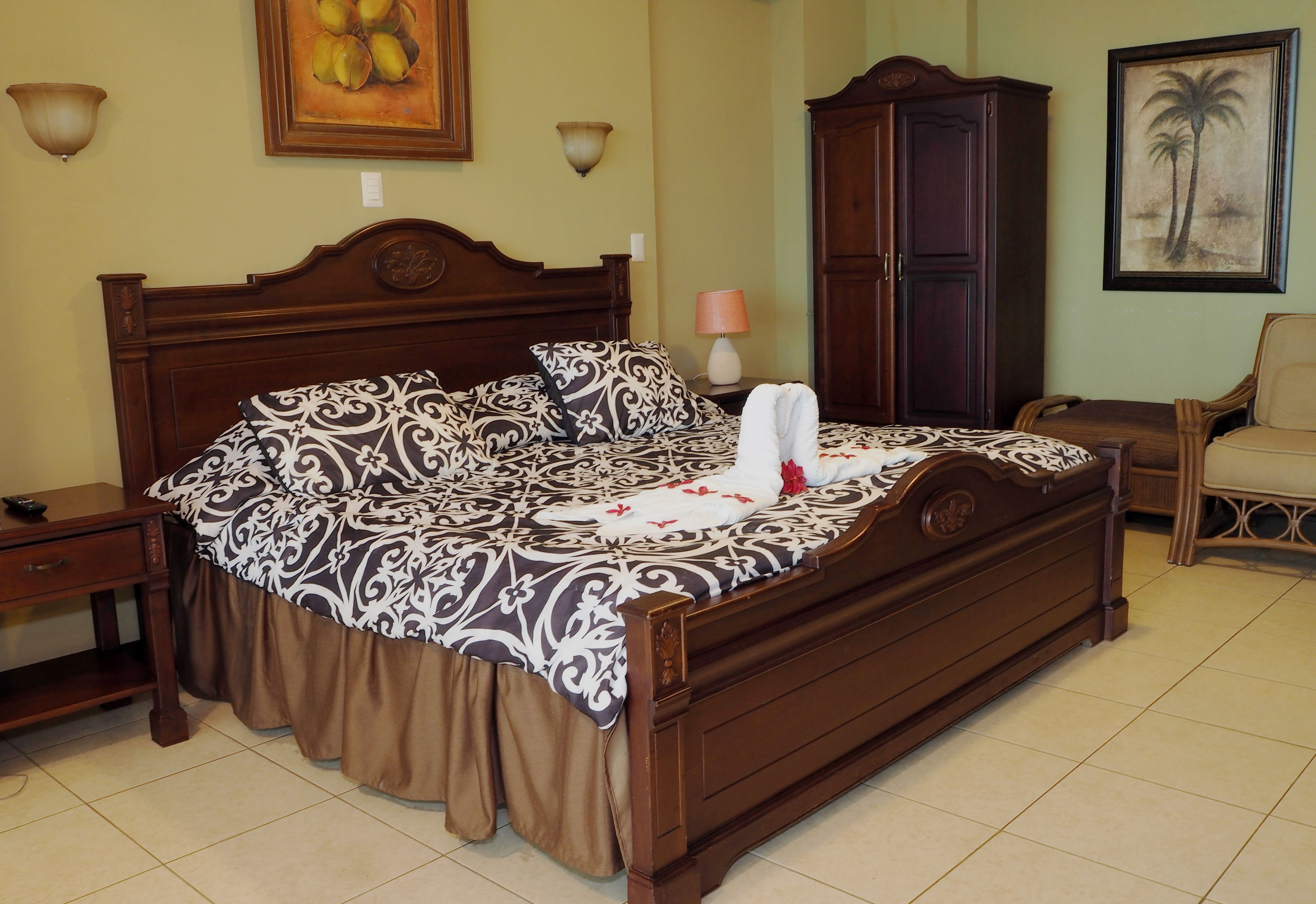 A neatly made bed with a patterned bedspread, a wooden headboard, and a nightstand with a lamp.