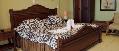 A neatly made bed with a patterned bedspread, a wooden headboard, and a nightstand with a lamp.