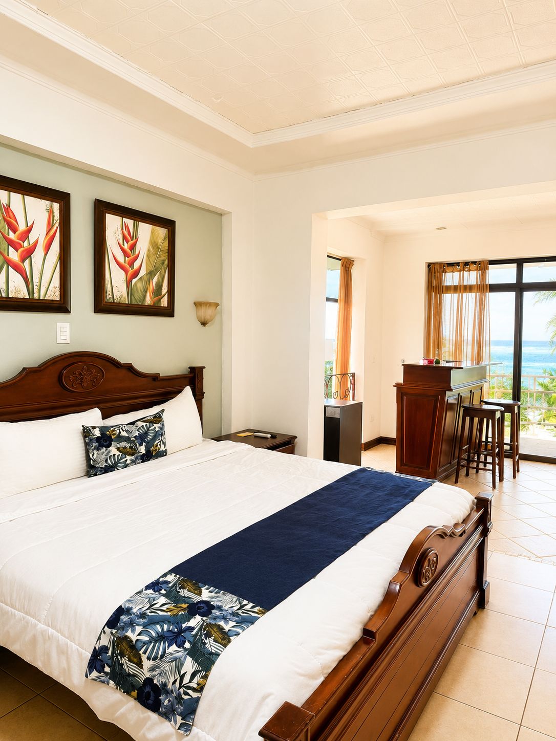 Una habitación de hotel con una cama grande, un escritorio con silla y vista al océano.