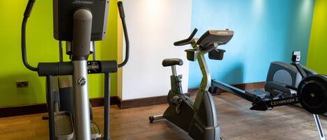 A gym with cardio machines, including an elliptical and a stationary bike, and a rowing machine.