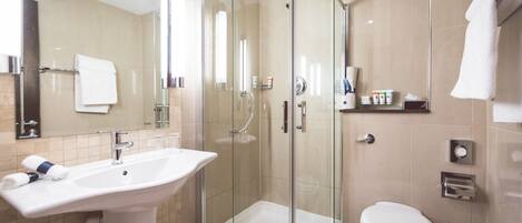 A modern bathroom with a glass-enclosed shower, a white sink, and a toilet.