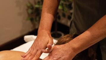 A person receiving a back massage in a room with a plant in the background.