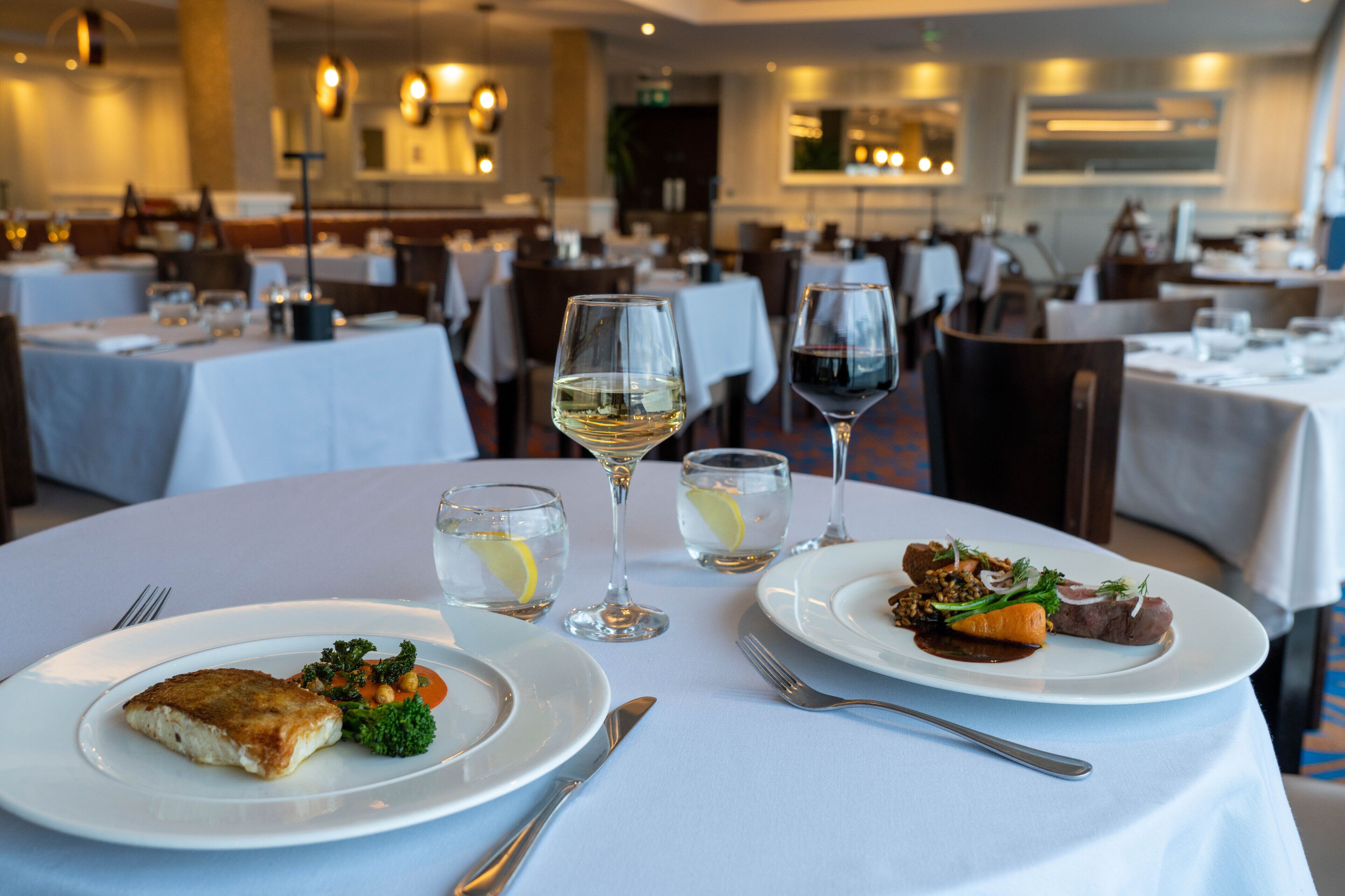 Une table à manger avec des assiettes remplies de nourriture, des verres à vin et des couverts.