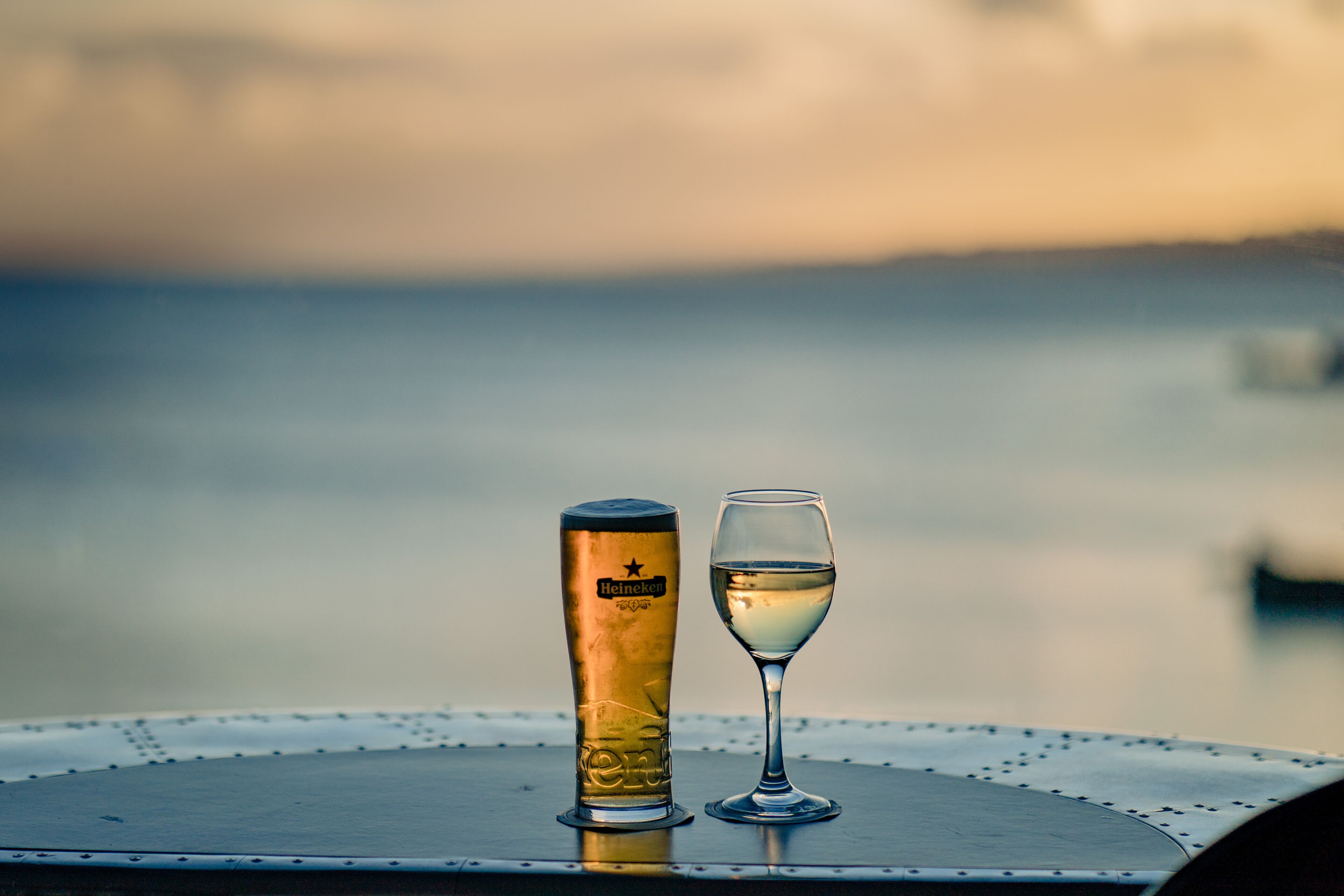 A table with a tall glass and a shorter glass, both on a metal table with a circular edge.
