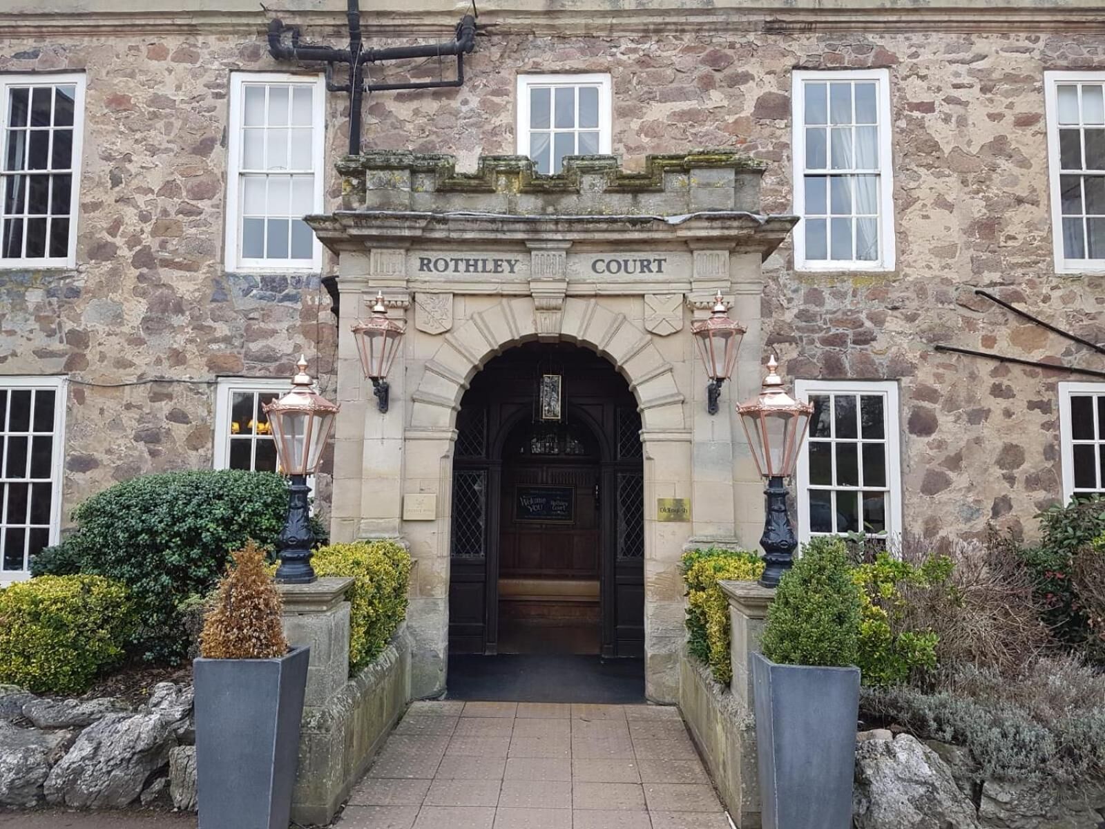 La entrada a Rothley Court, con fachada de piedra, arco de entrada y dos luces de estilo farol.