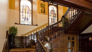Una gran escalera con detalles de madera ornamentados y vidrieras de colores.