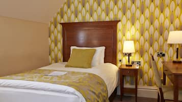 Une chambre d’hôtel avec un lit, une table de chevet, un bureau et une chaise.