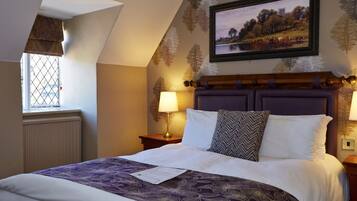 A bedroom with a large bed, a window with a view of the countryside, and a framed picture on the wall.