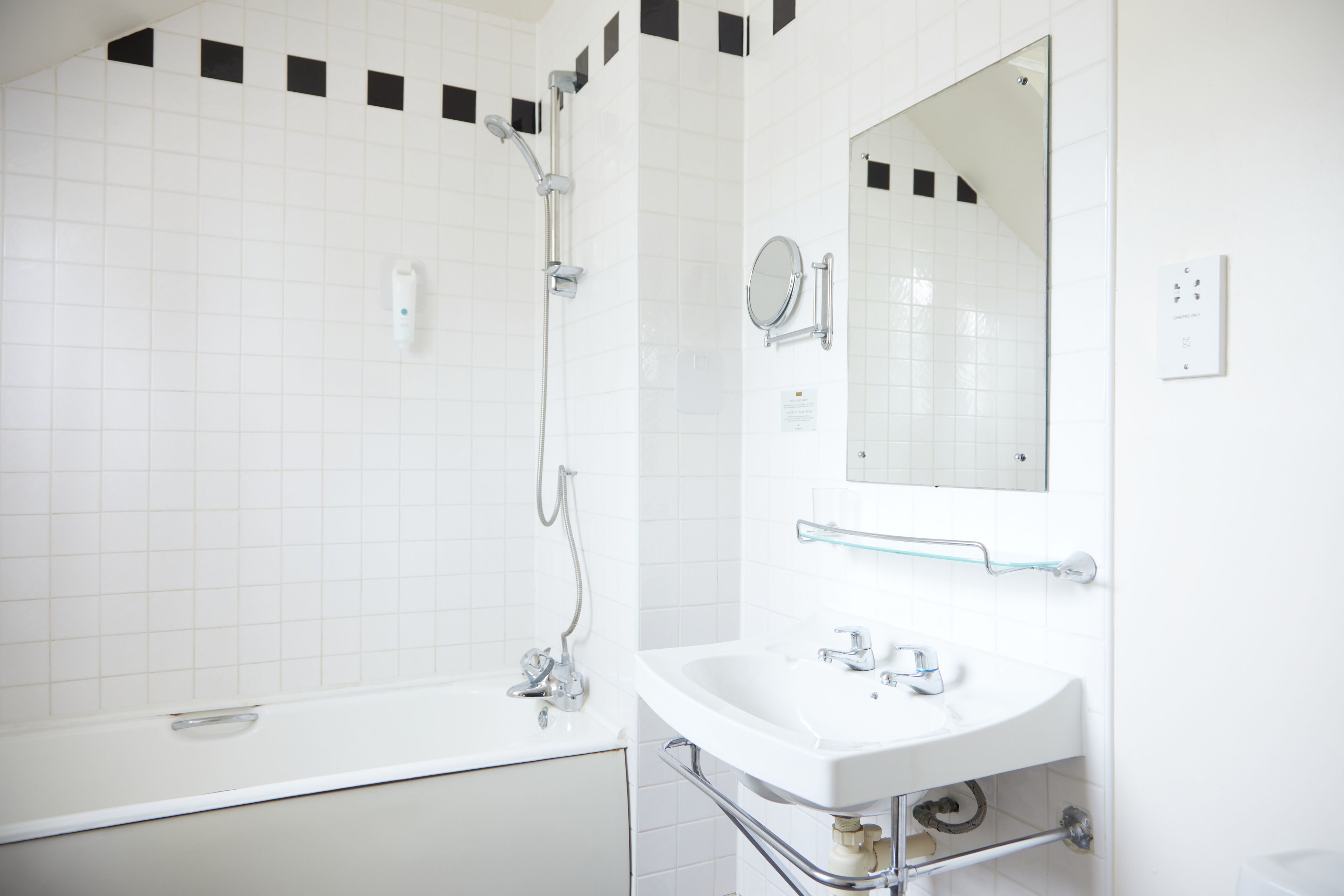 Ein Badezimmer mit einer weißen Badewanne, einem Waschbecken mit Spiegel und einer Glasdusche.