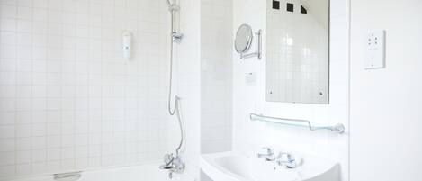 A bathroom with a white bathtub, a sink with a mirror, and a glass shower enclosure.