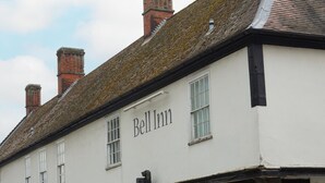 A traditional building with the name "Bell Inn" on its facade, featuring a classic architectural style with a tiled roof and multiple chimneys.
