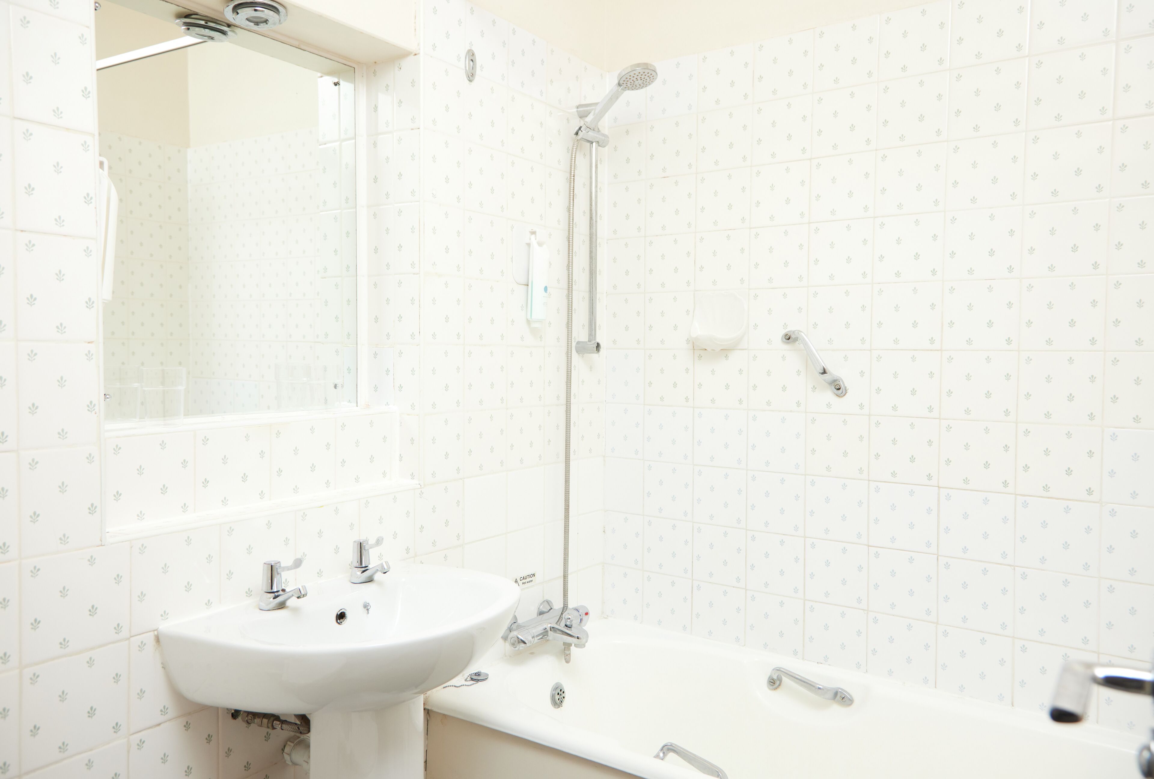 Une salle de bain équipée d’un lavabo, d’un miroir, d’une douche et de toilettes.