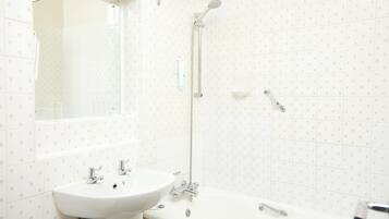 Une salle de bain équipée d’un lavabo, d’un miroir, d’une douche et de toilettes.