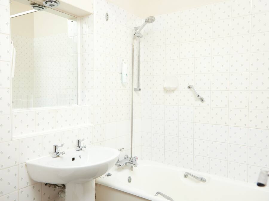 Une salle de bain équipée d’un lavabo, d’un miroir, d’une douche et de toilettes.