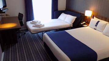 Una habitación de hotel con cama, escritorio, silla y televisión.
