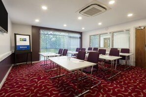 A conference room with a red patterned carpet, white tables, and purple chairs. - Holiday Inn Express Dunstable by IHG (Dunstable)