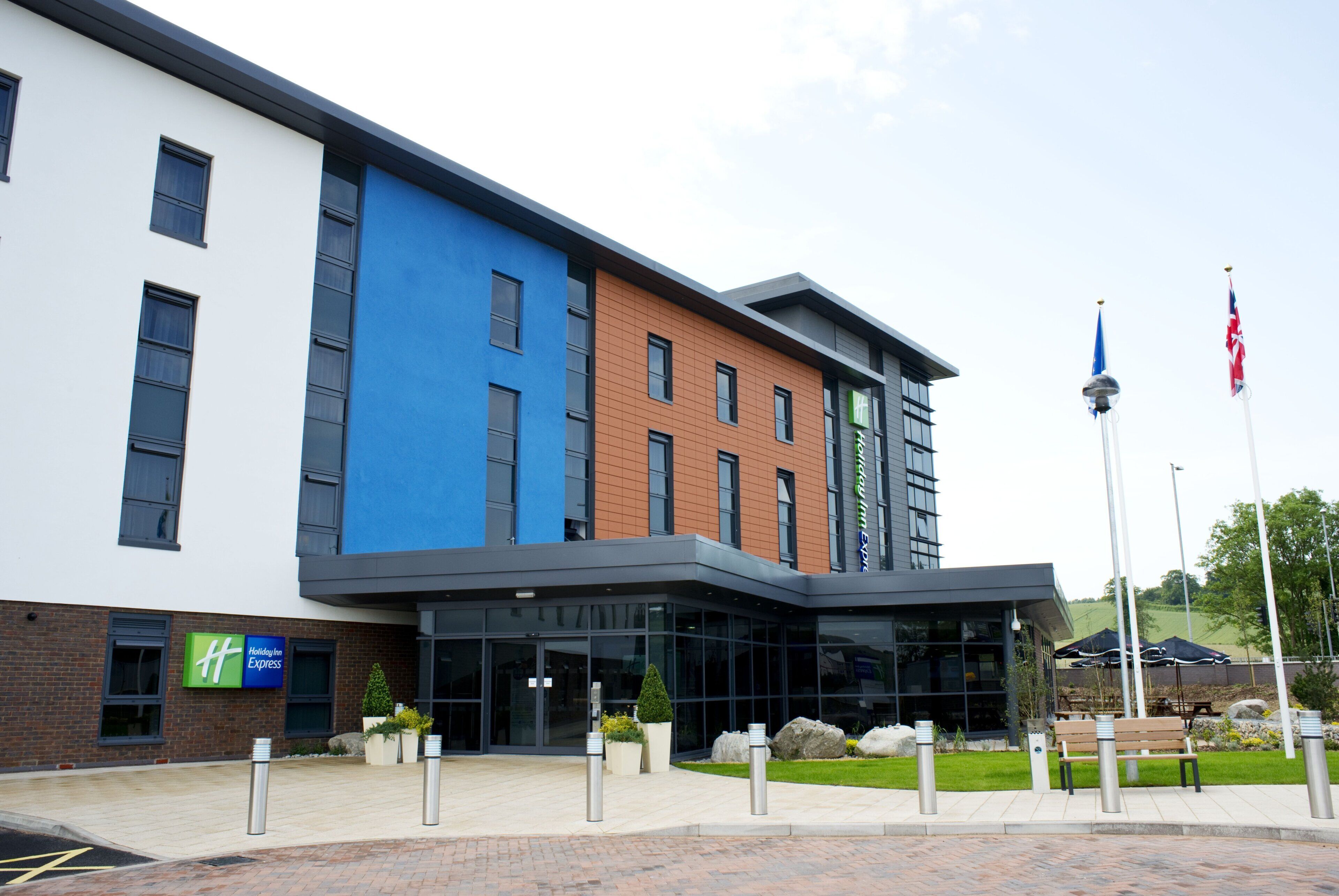 A modern building with a Holiday Inn Express sign, large windows, and a landscaped entrance area.