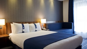 Et hotelværelse med en stor seng, to sengeborde, et skrivebord og en stol.