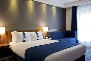 Una camera d'albergo con un letto grande, due comodini, una scrivania e una sedia.