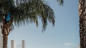 A pool area with lounge chairs, palm trees, and a view of buildings. - Hotel Sao Sebastiao de Boliqueime (Loulé)