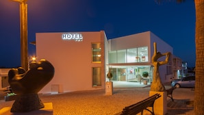 A modern hotel with a sign, a sculpture, and a bench in front. - Hotel Sao Sebastiao de Boliqueime (Loulé)