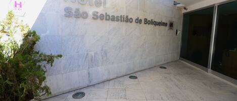A hotel entrance with a marble wall displaying the name "Hotel São Sebastião de Boliqueime."