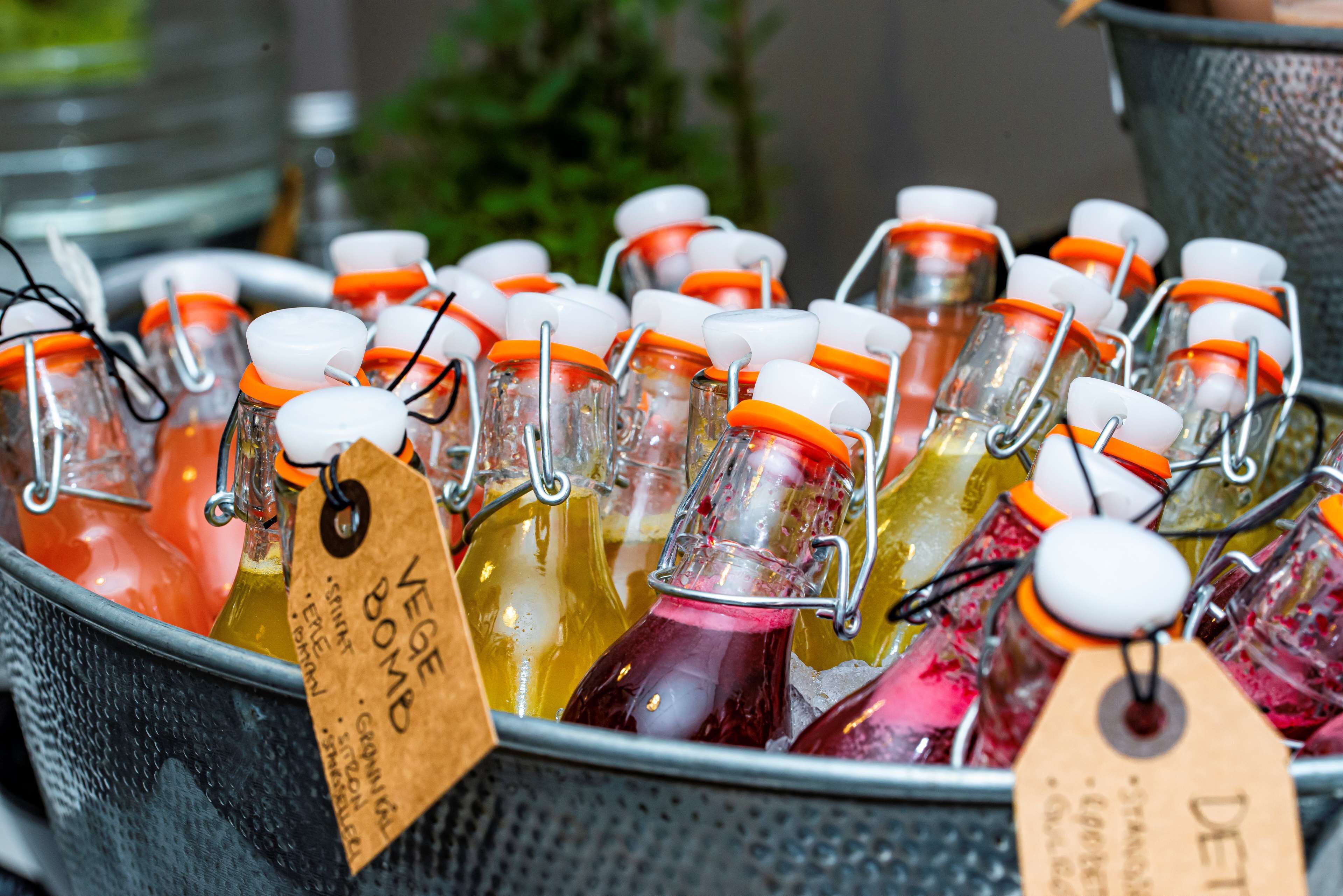 A metal container filled with glass bottles of beverages, each with a tag.