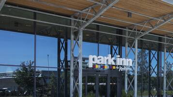 Un edificio moderno con un amplio frente de vidrio, techo de listones de madera y un letrero que dice "Park Inn".
