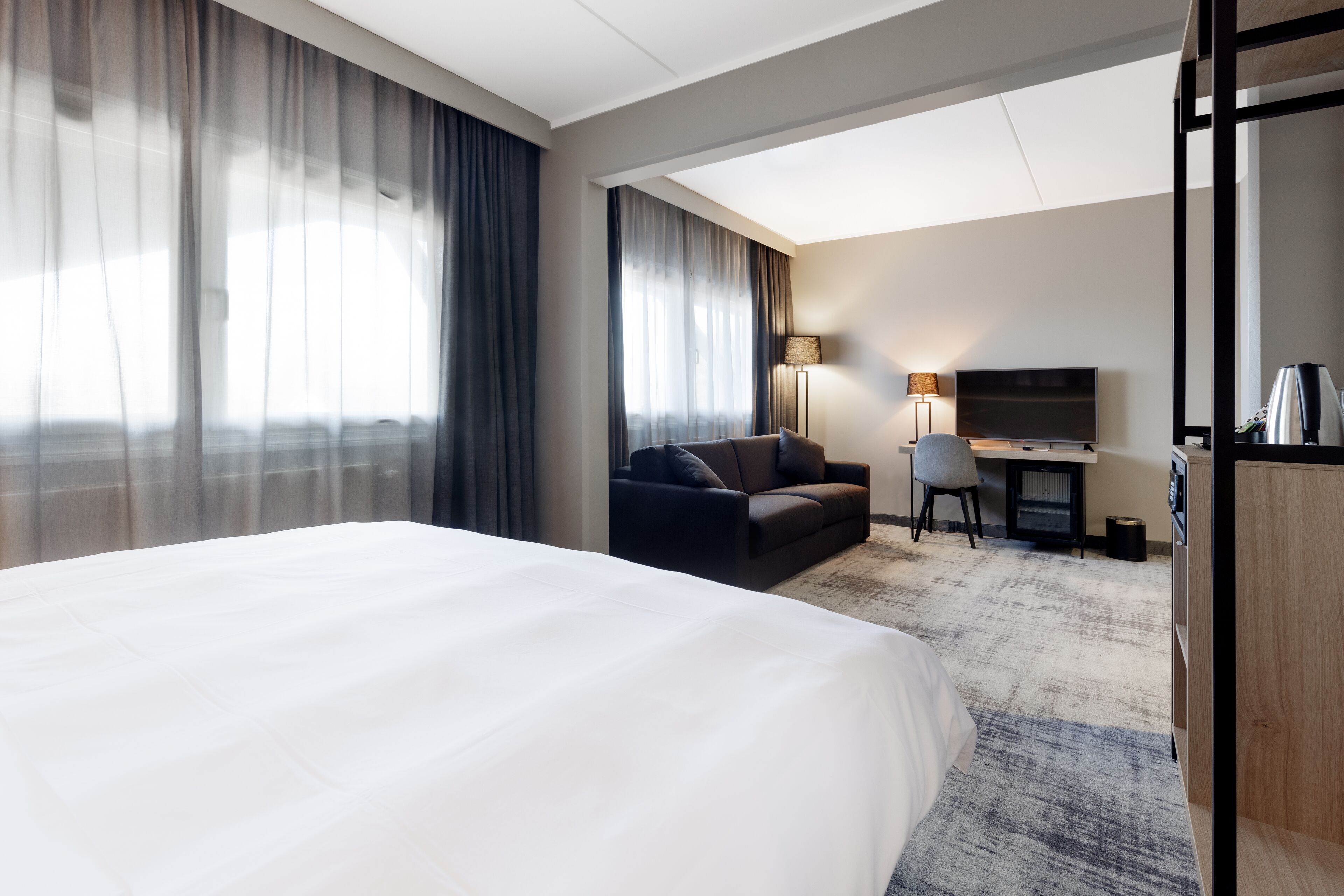 Une chambre d’hôtel avec un grand lit, un bureau, une chaise et un téléviseur.