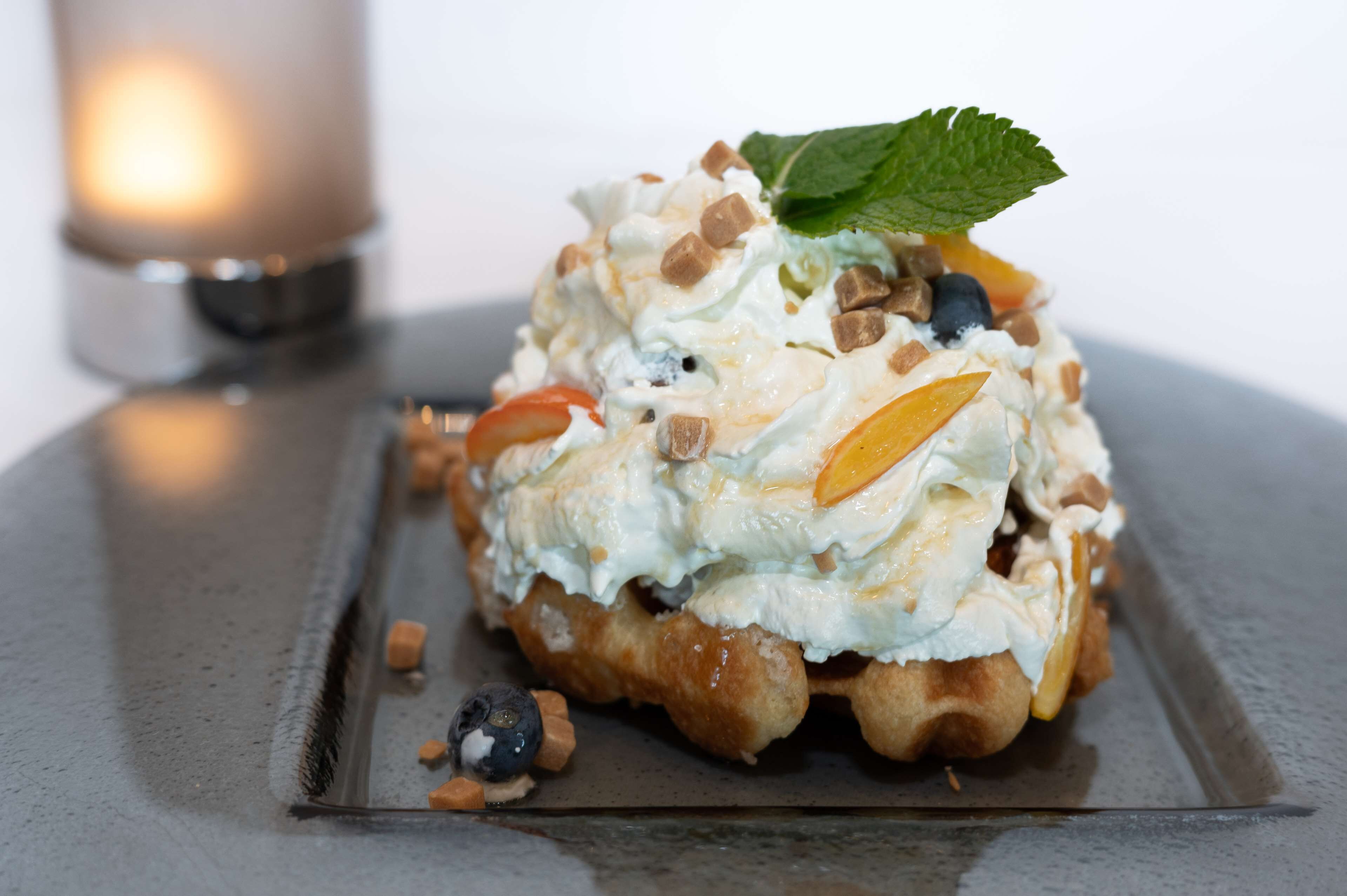 A dessert on a plate with a candle in the background.