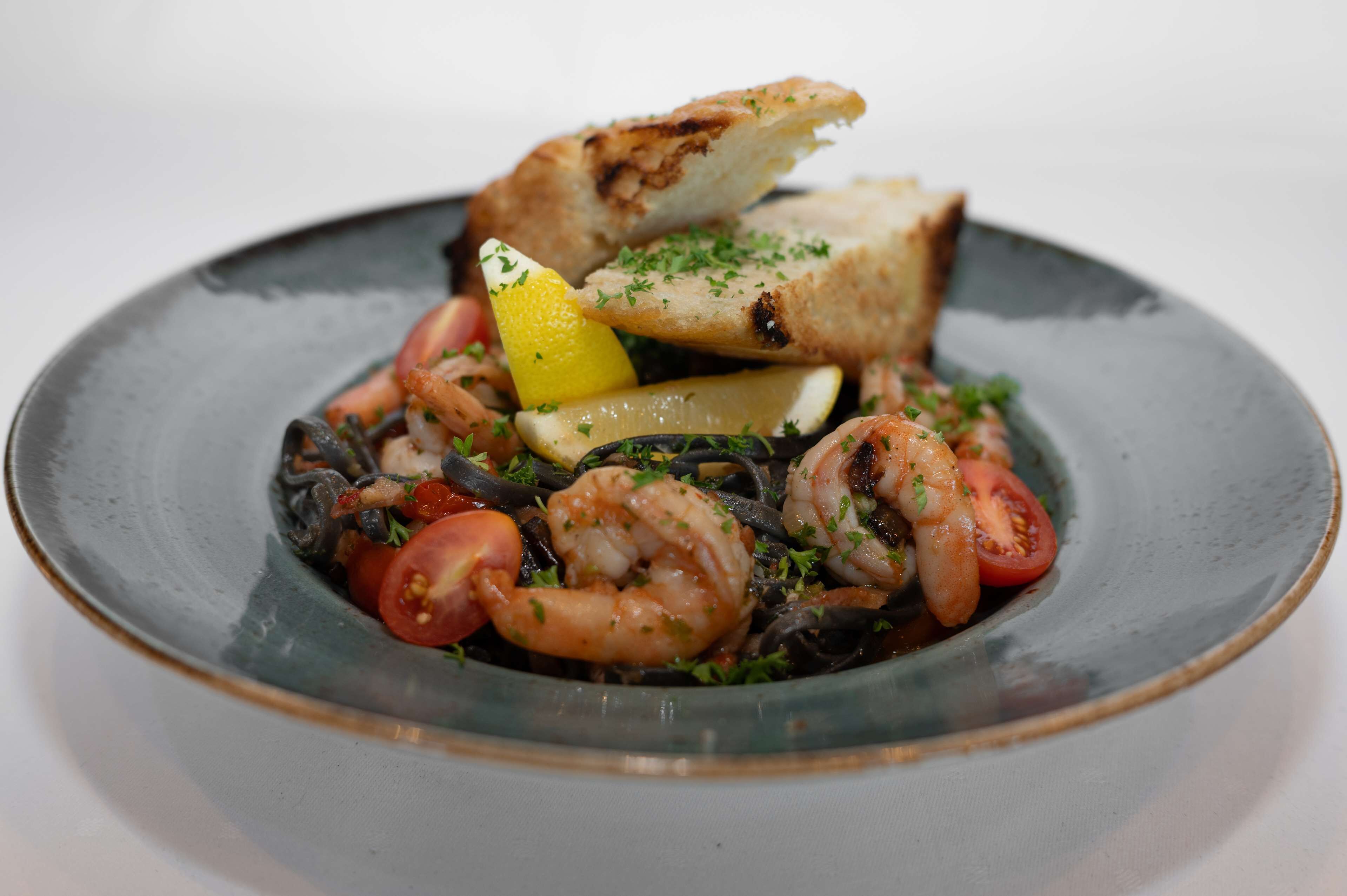 A seafood dish with shrimp, mussels, and lemon slices on a plate.
