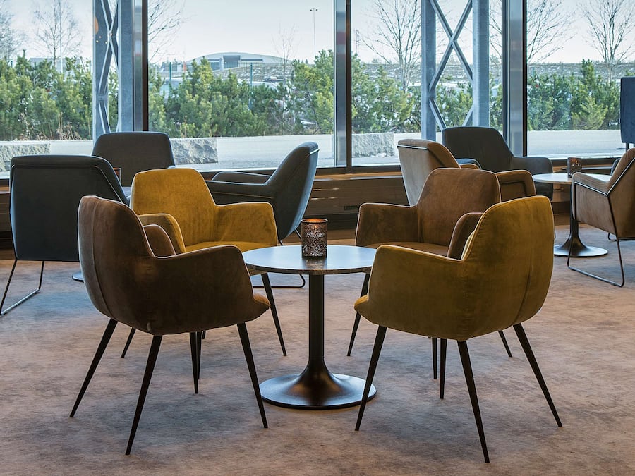 A modern interior with large windows, multiple seating arrangements, and hanging pendant lights.