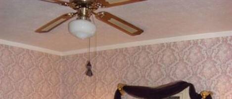 A bedroom with a four-poster bed, a ceiling fan, and two bedside lamps.