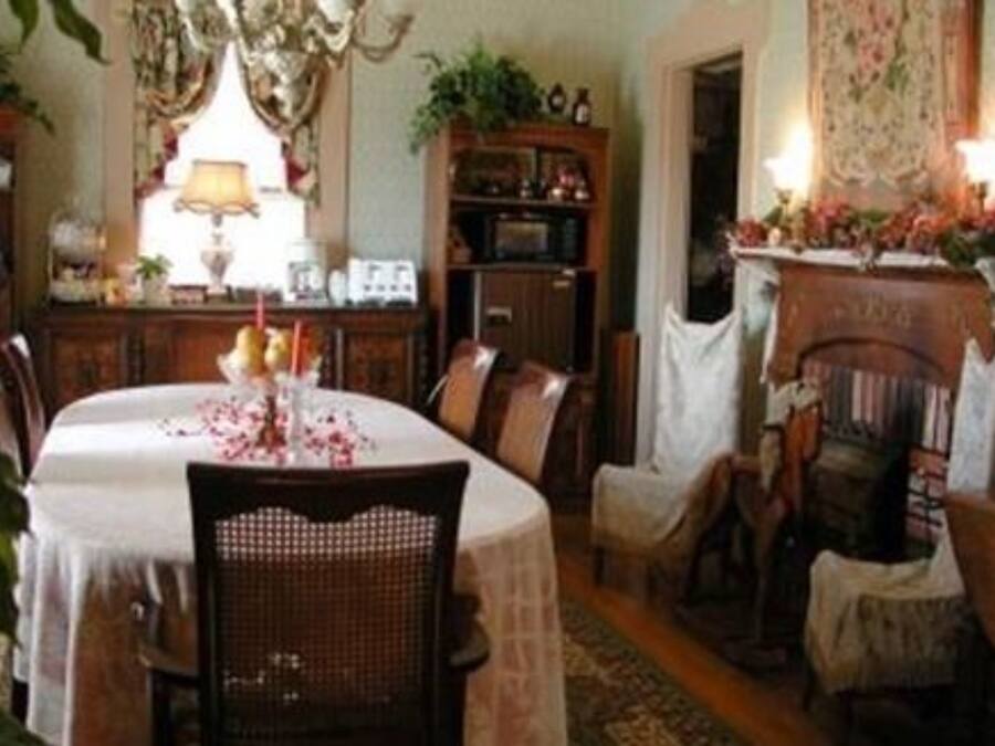 A dining area with a round table, chairs, a fireplace, and a bookshelf.