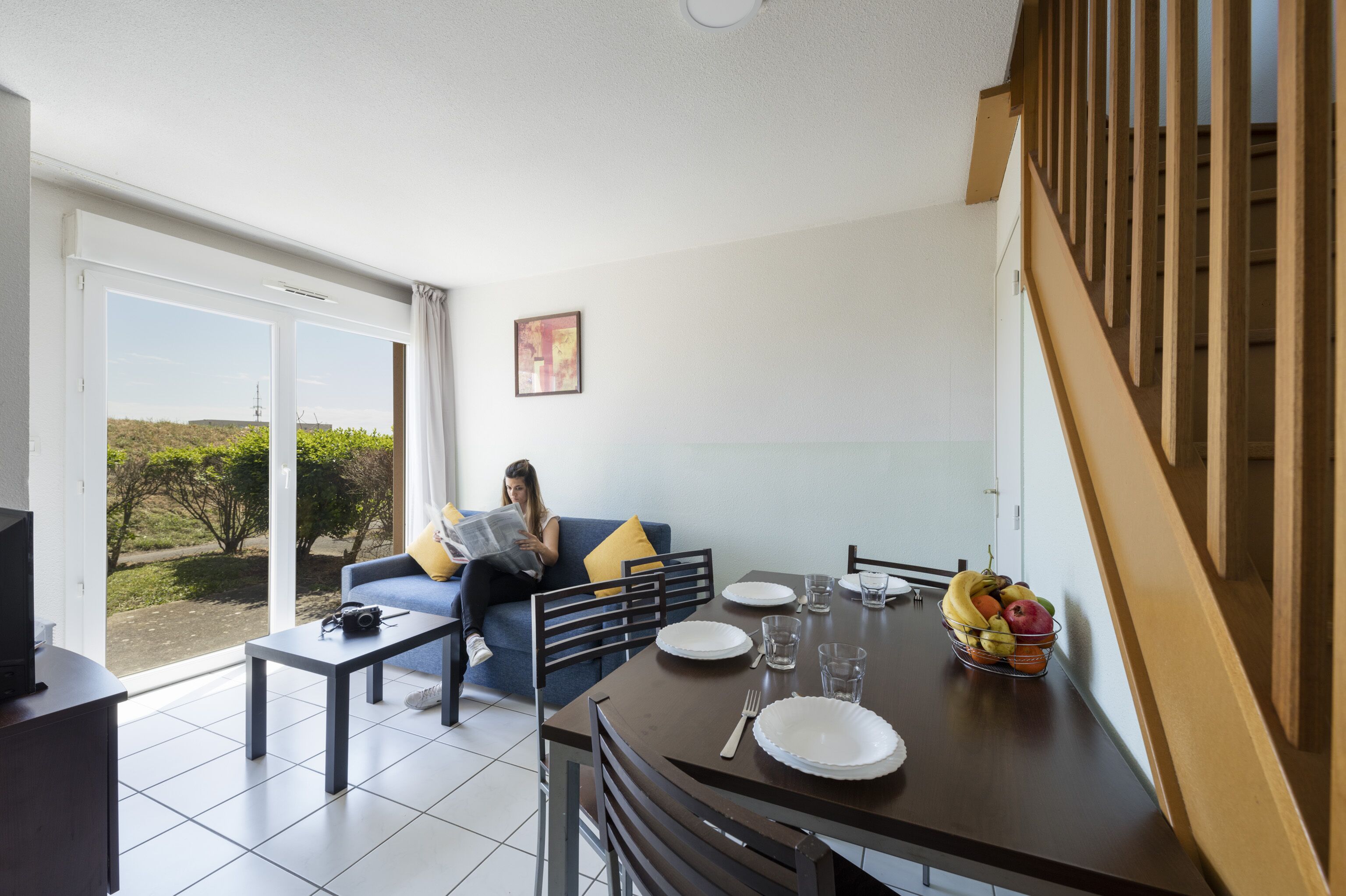 A modern living room with a sofa, coffee table, and dining table set for two.