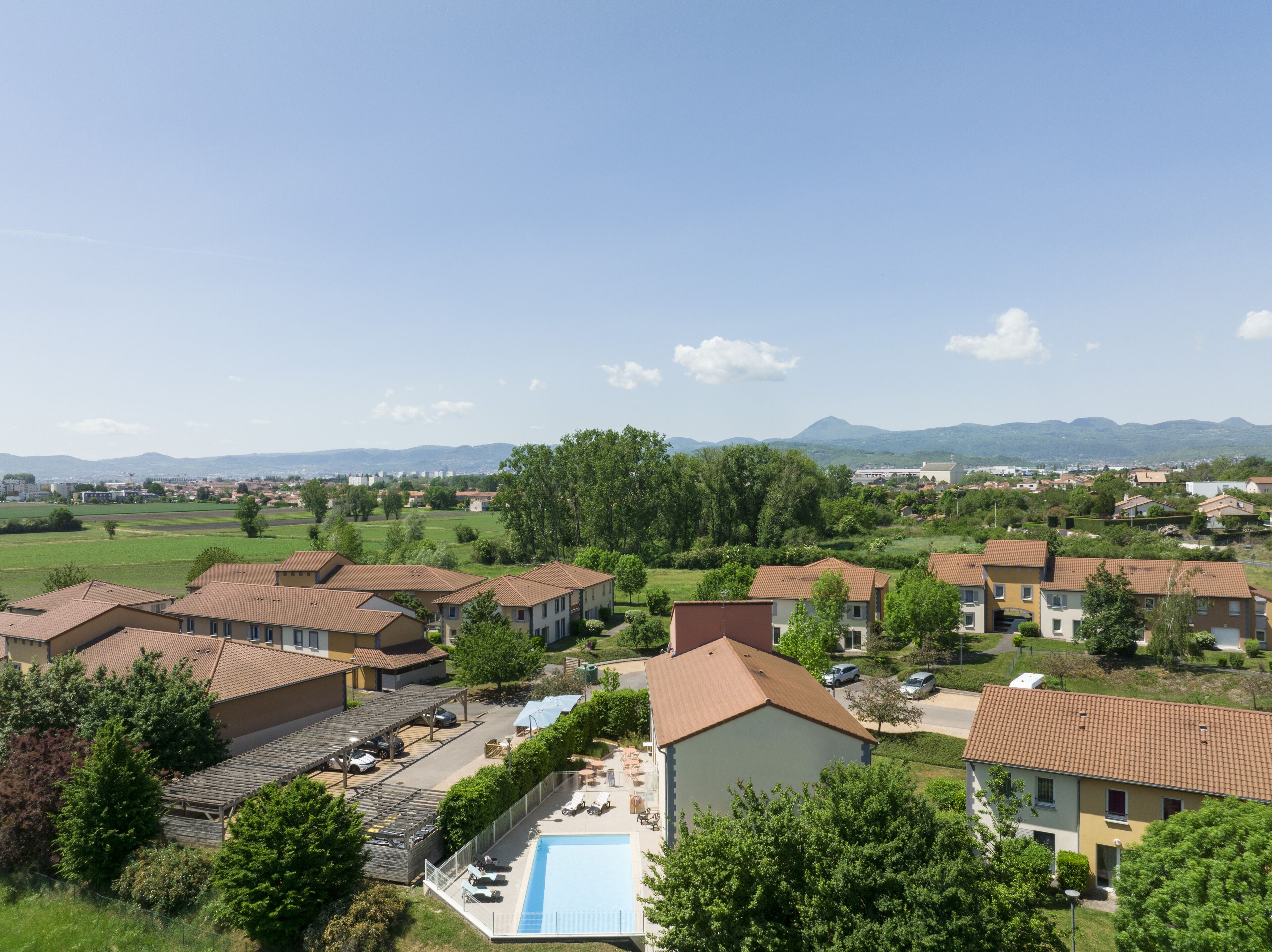 A residential area with multiple houses, a swimming pool, and a view of distant mountains.