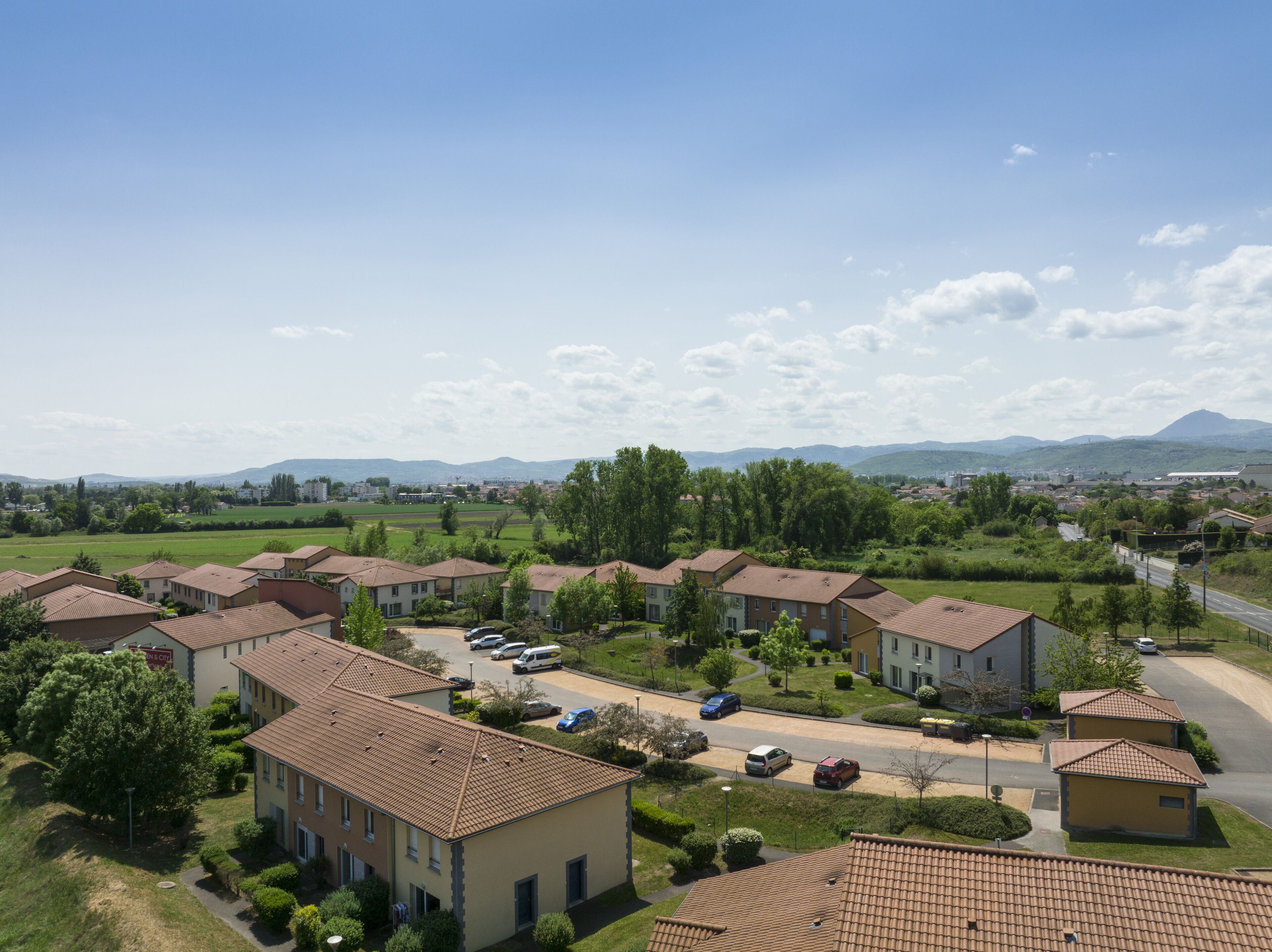 A residential area with multiple two-story houses, a main road, and distant mountains.