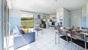 A modern apartment with a dining area, kitchen, and a balcony with a view of the garden.