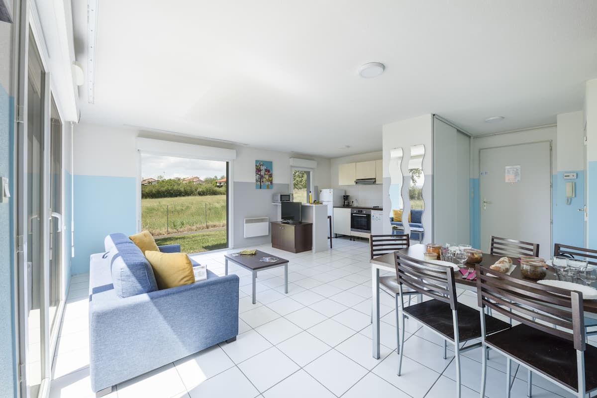 Un appartement moderne comprenant un coin repas, une cuisine et un balcon avec vue sur le jardin.