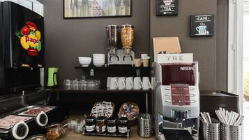 A coffee station with a Nescafe machine, jars of condiments, and a basket of pastries.