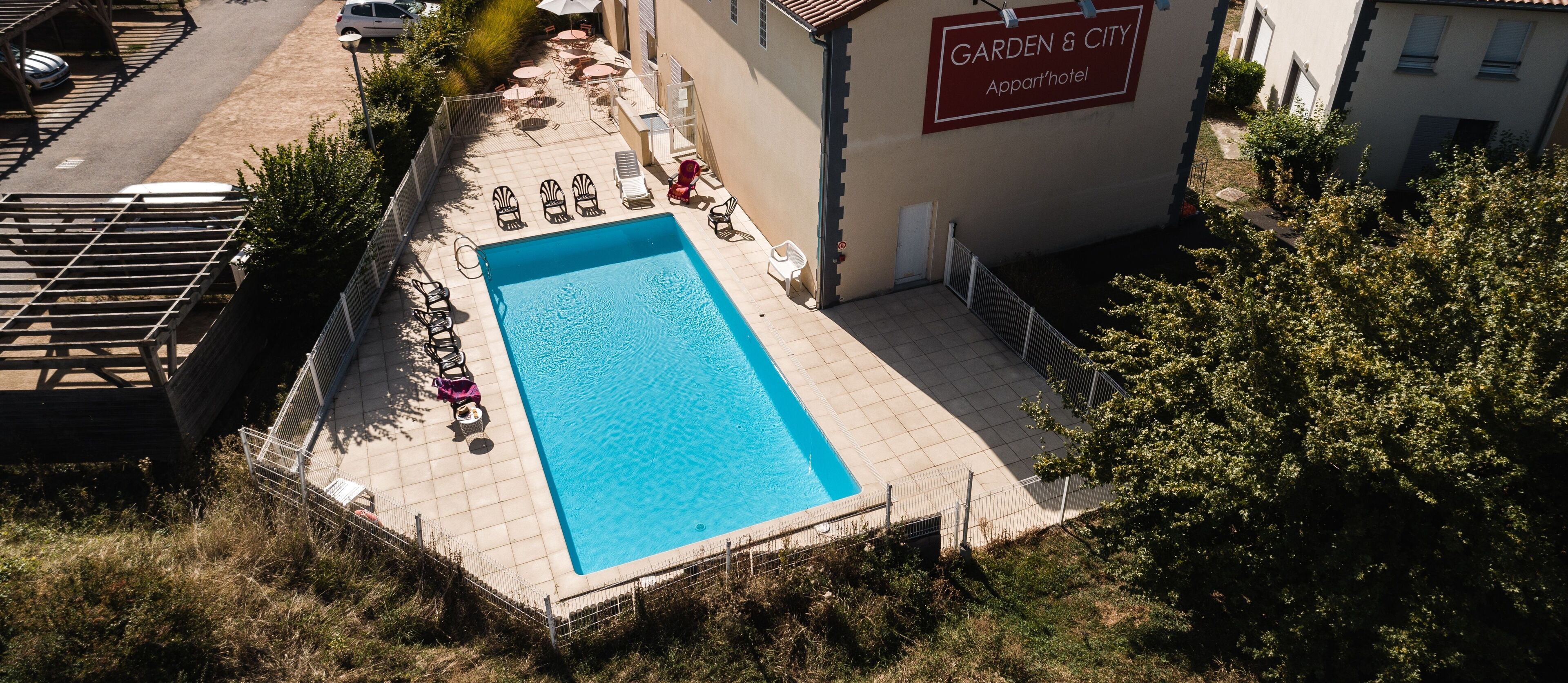 A rectangular pool with lounge chairs and umbrellas, surrounded by a fence, with a building labeled "Garden & City Apartments" in the background.