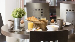 A breakfast table with croissants, eggs, juice, and a small potted plant.