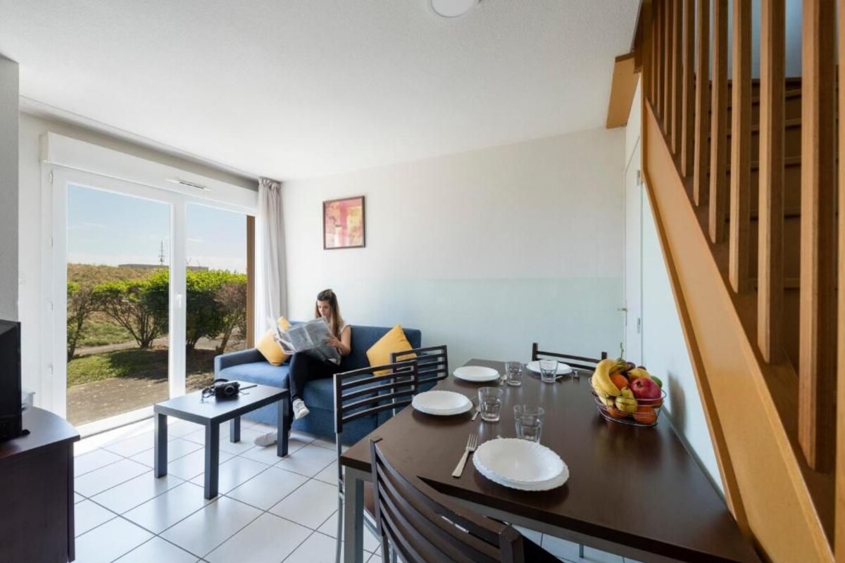 A modern living room with a sofa, coffee table, and dining table set for two.