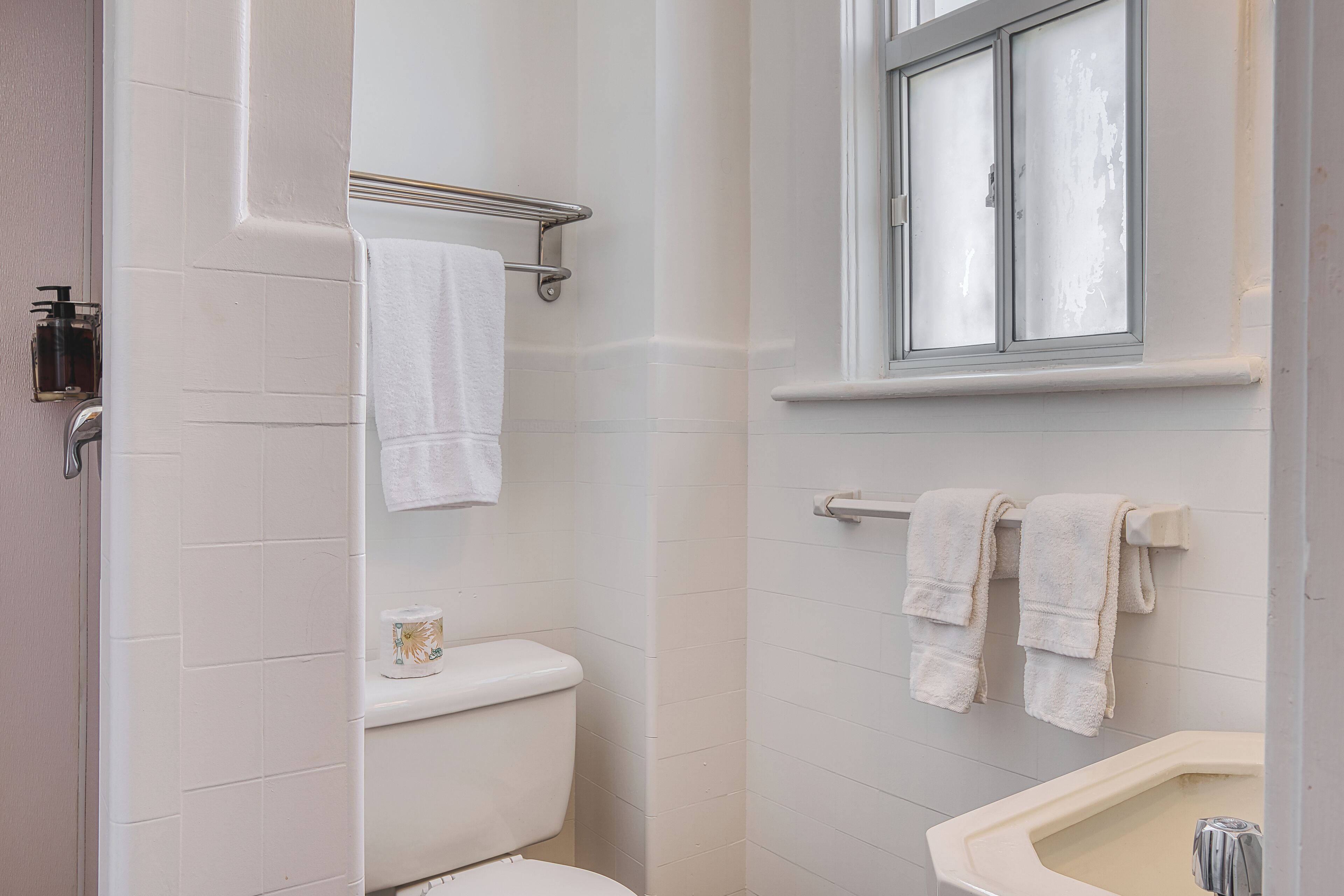A bathroom with a toilet, a sink, and a window.