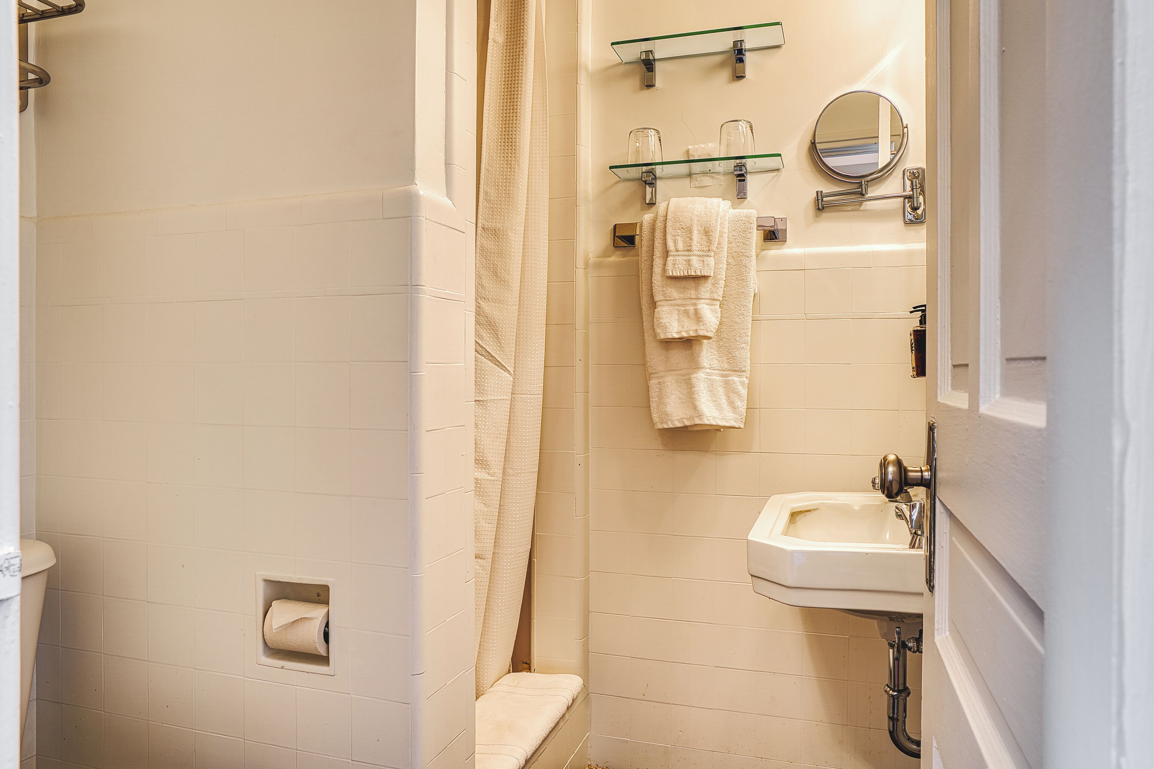 Un baño con inodoro, ducha con puerta de vidrio, lavamanos y espejo.