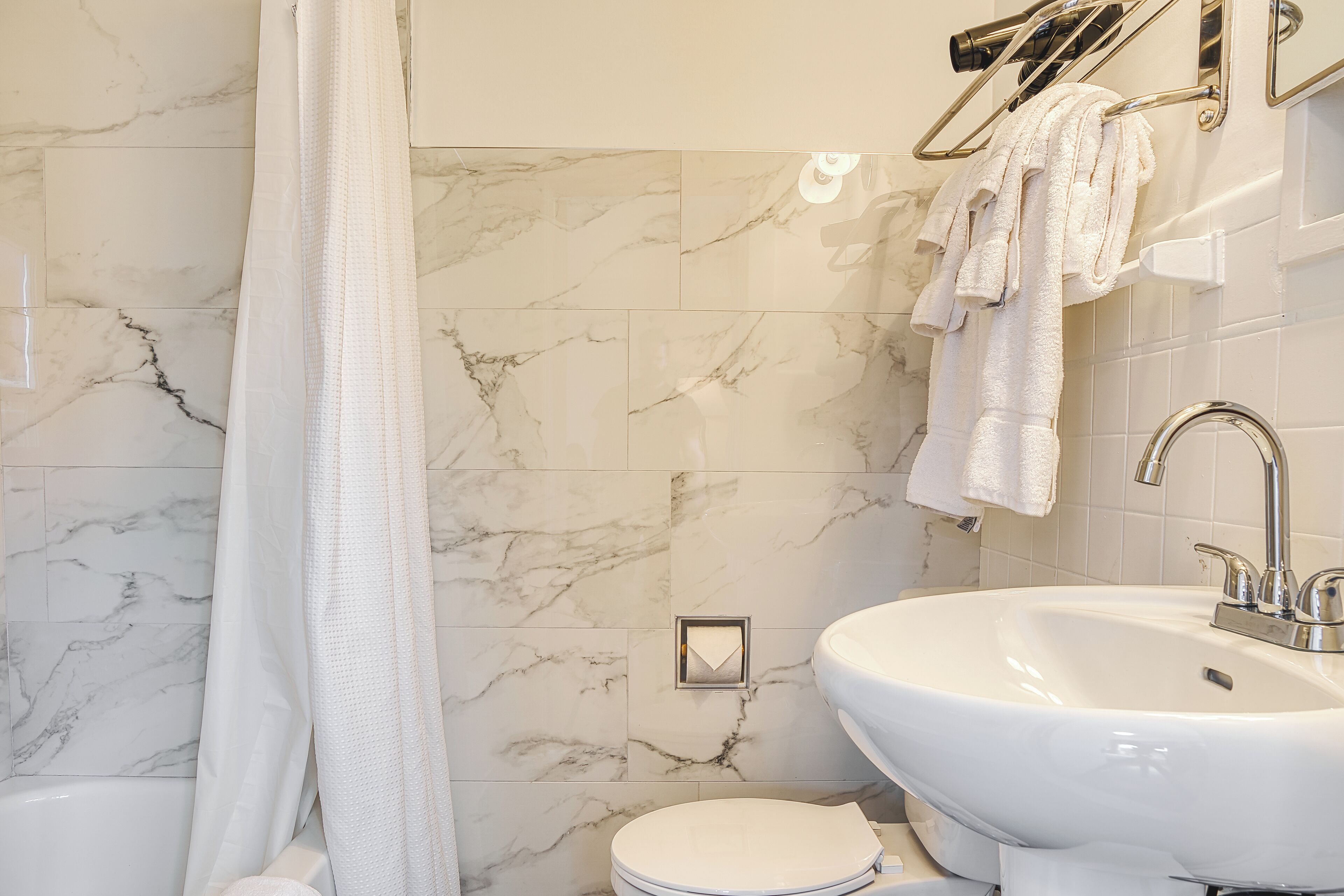 Une salle de bain avec une baignoire blanche, un lavabo et des toilettes.