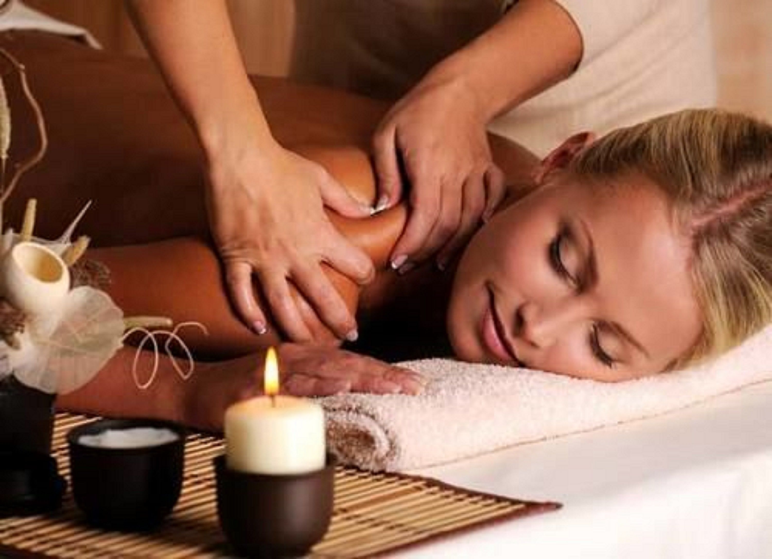 A person receiving a massage, with a candle and a small bowl on the table.