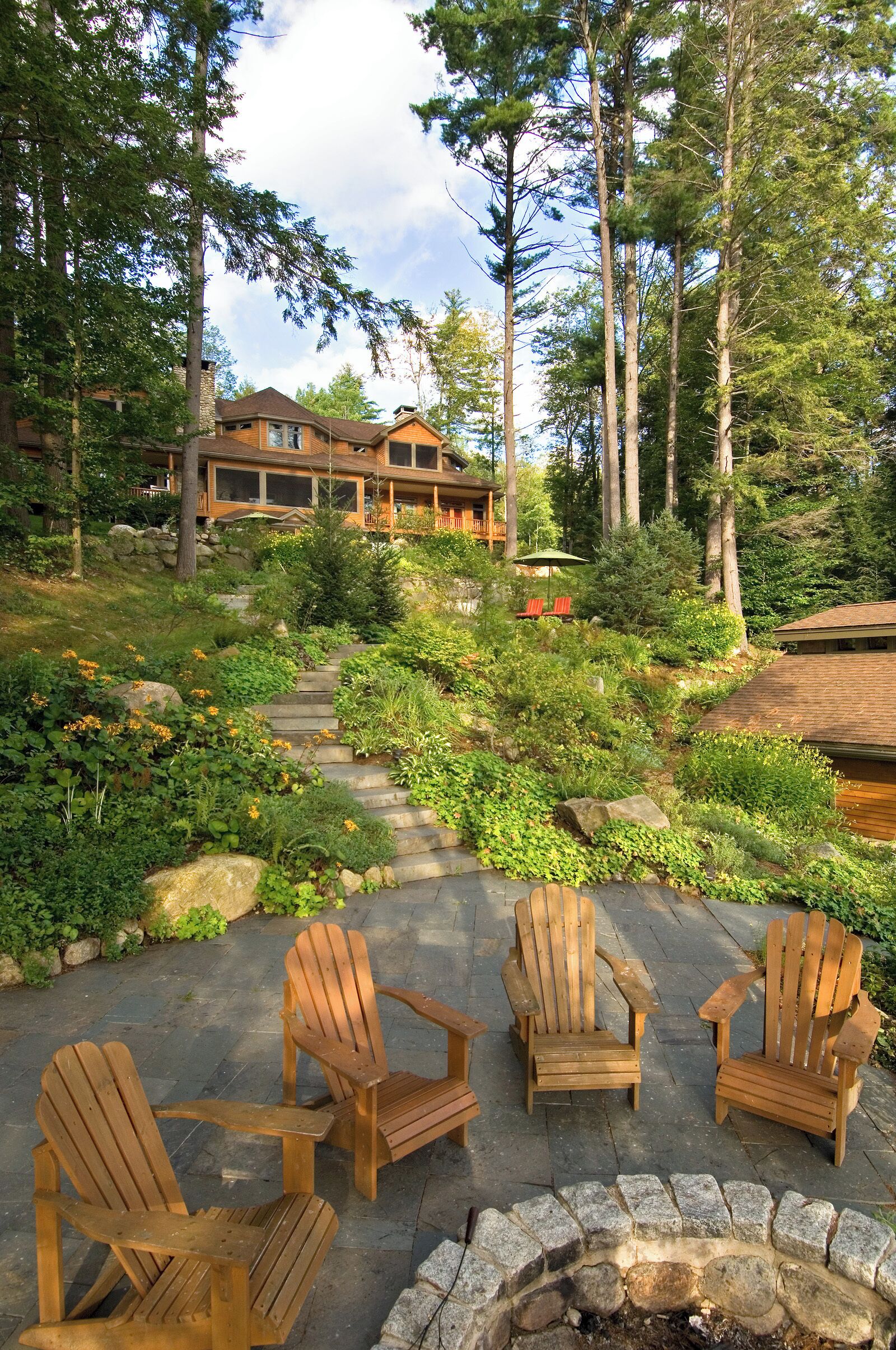 A wooden deck with Adirondack chairs and a stone fire pit.