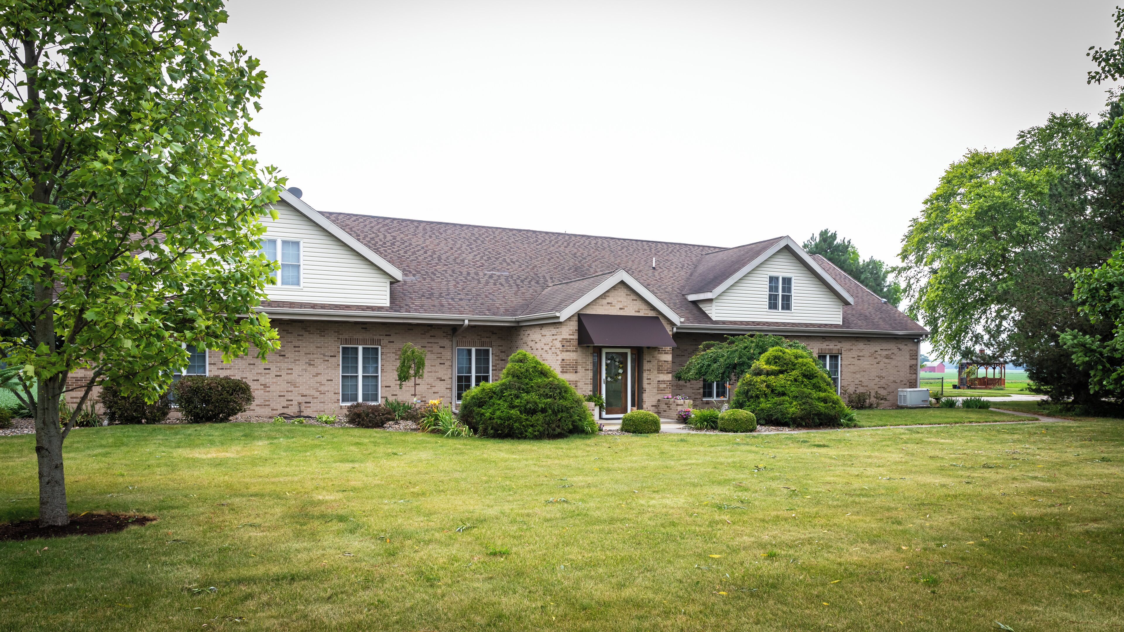 A two-story house with a brick facade, a dark roof, and a front porch.