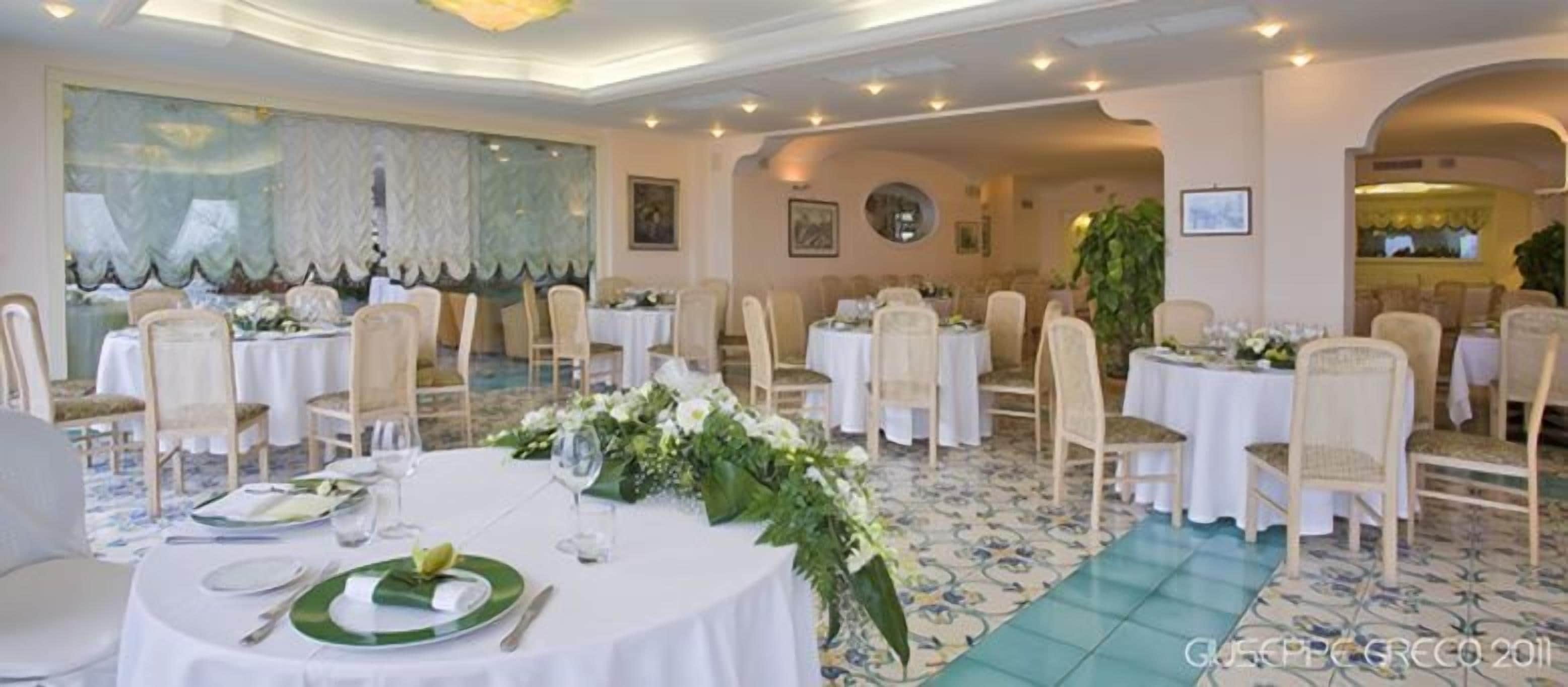 A banquet hall with round tables, white tablecloths, and floral centerpieces.